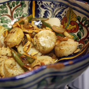 Scallops with roasted garlic, jalapeños, and toasted almonds in a decorative bowl.